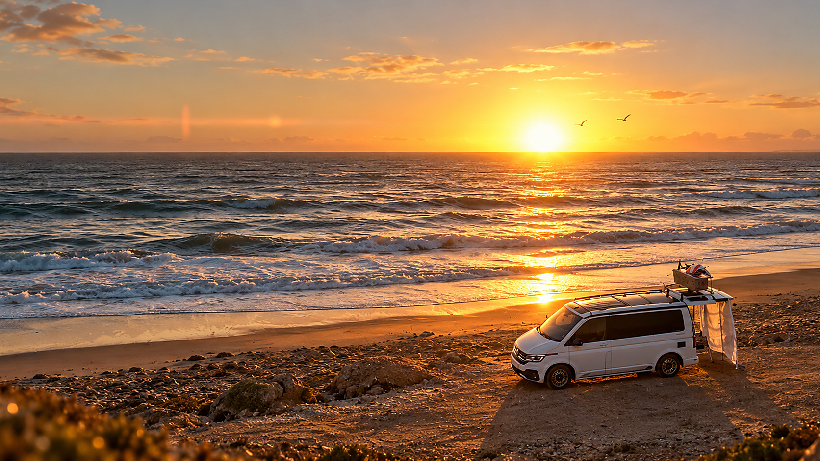 Der Campingbus klein am Rand eines weiten Sandstrandes bei Sonnenuntergang am Atlantik