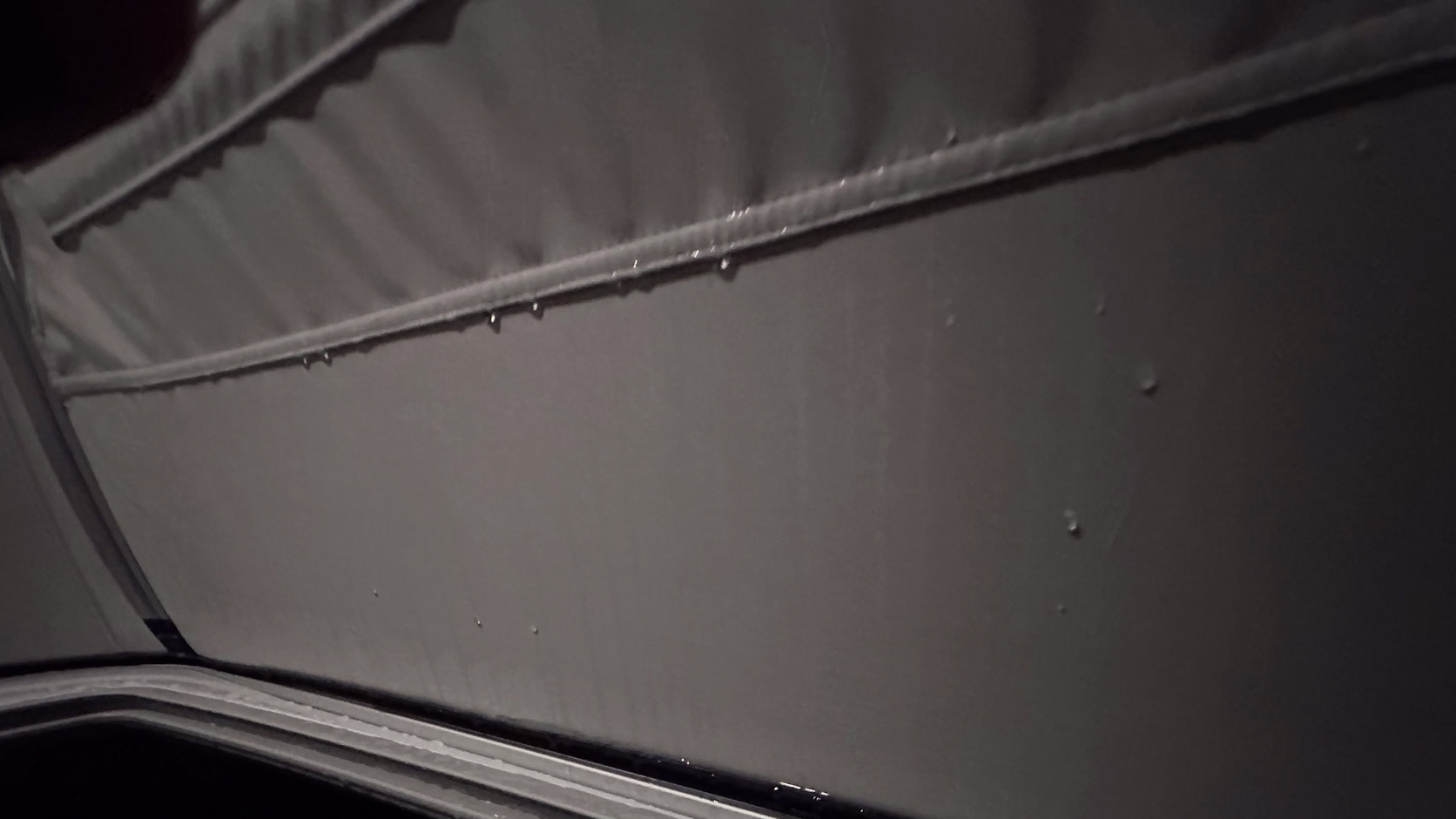 Nahaufnahme der Kante des Aufstelldachs, an der Naht hängen Wassertropfen.