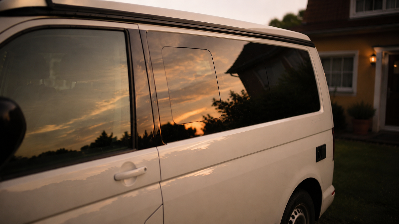 Detail eines alten Campingbusses im warmen Abendlicht vor dem Haus
